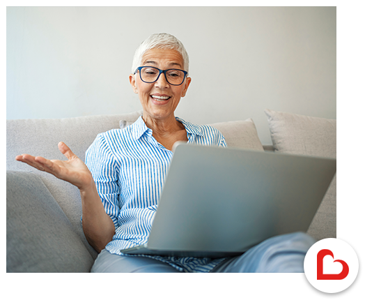 older woman with glasses smiling and looking at laptop
