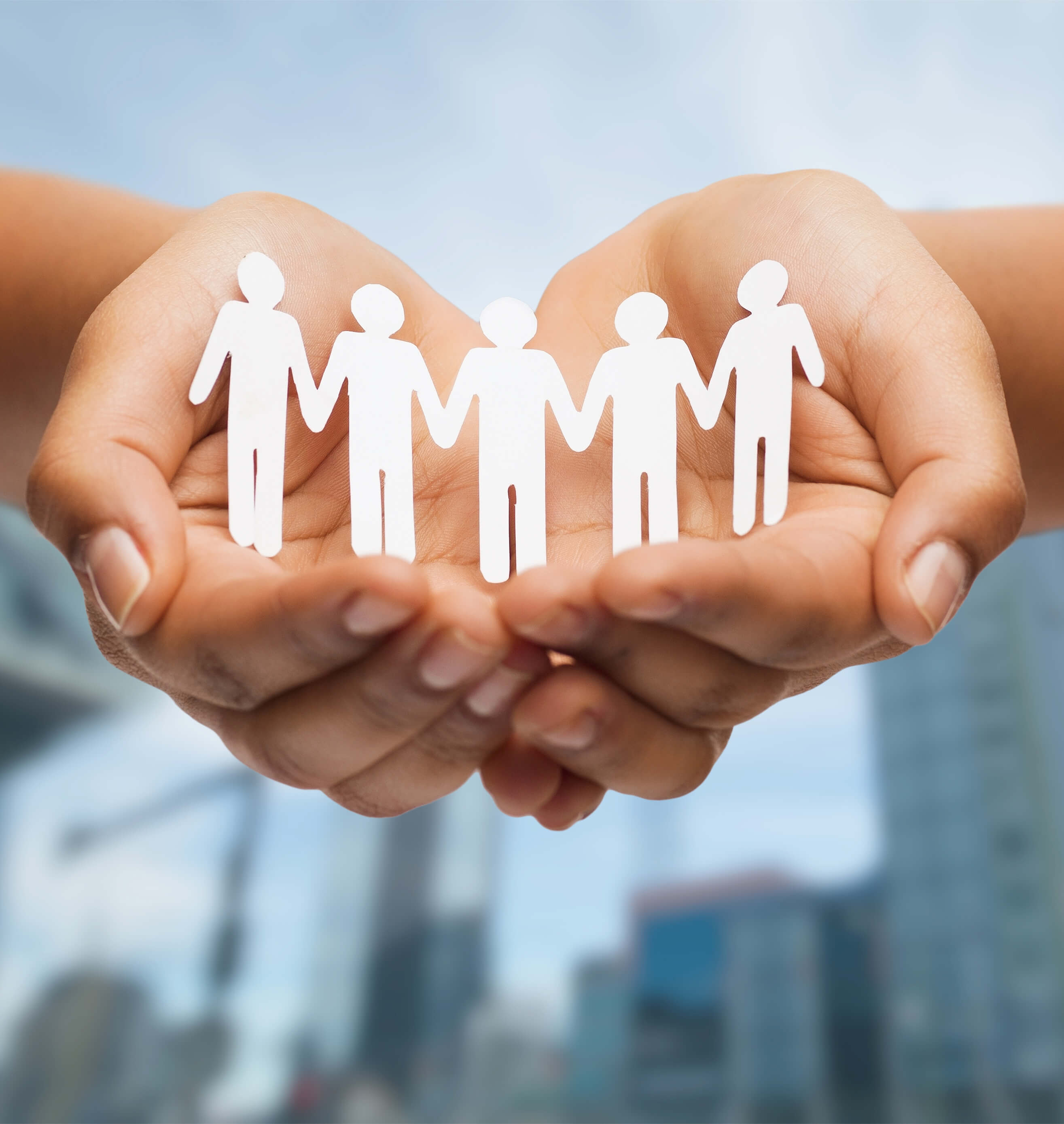 Cupped hands holding five white paper cut-out figures with a blue blurred background