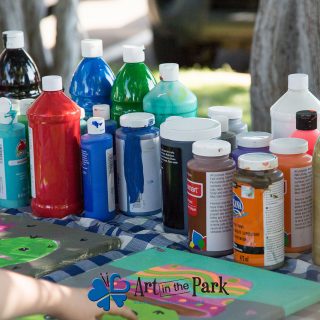 Art in the Park 2021 paints and childs hand on a painting